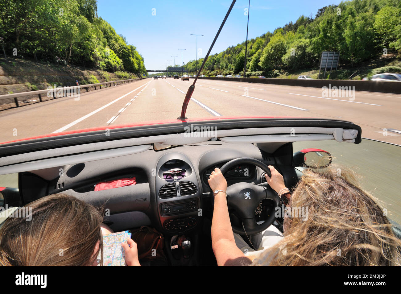 Open top coche con conductor y pasajero femenino en carretera abierta Foto de stock