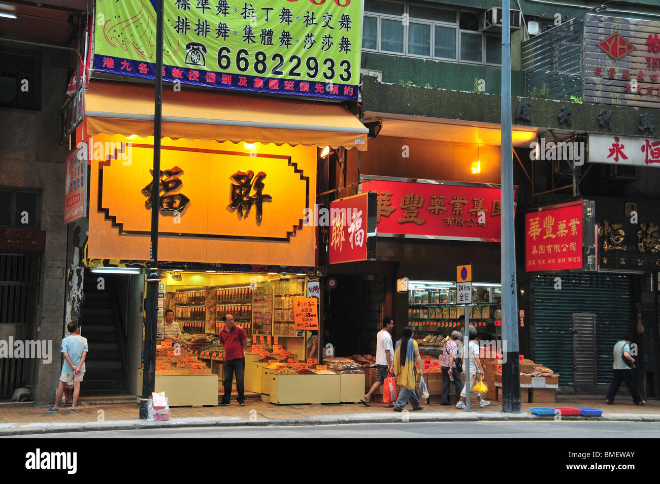 Dos amarillos, rojos, iluminados, de fachada abierto tiendas que venden pescados y mariscos secos, Des Voeux Road West, Sai Ying Pun, Hong Kong Foto de stock