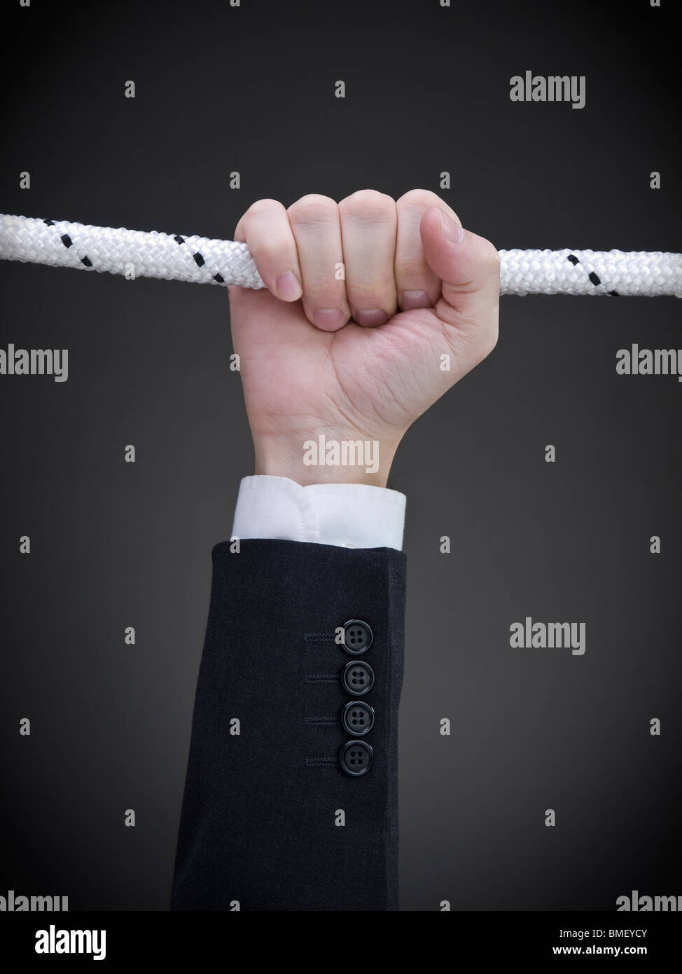 Primer plano de la mano de un empresario colgando de una cuerda. Foto de stock