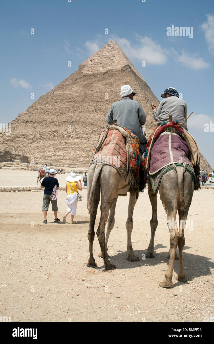 Dos jinetes de camellos y turistas en frente de la pirámide de Khafre (Chephren) en Giza Egipto Foto de stock