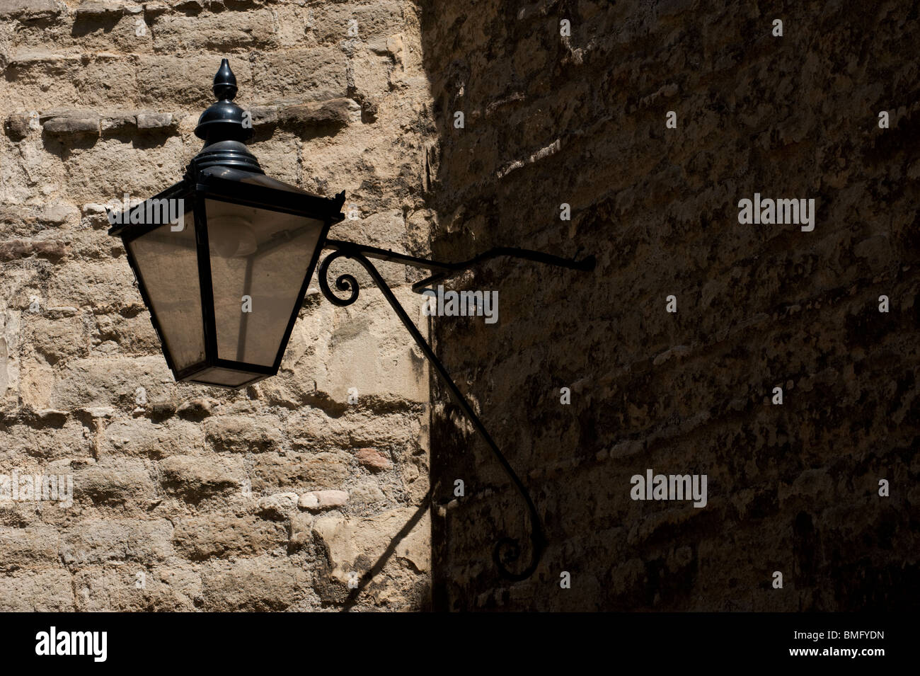 Una lámpara de la calle Herrería fijado contra un muro de piedra en el Queen's Lane, Oxford Foto de stock