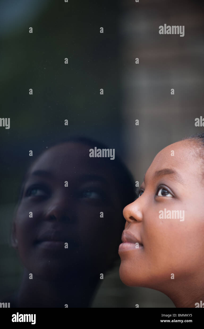 Mujer joven mirando hacia la ventana con la reflexión, Johannesburgo, en la provincia de Gauteng, Sudáfrica Foto de stock