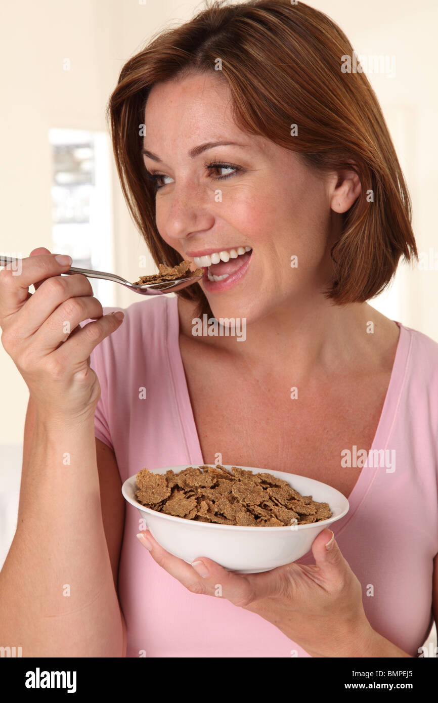 Mujer comiendo hojuelas de salvado de cereal de desayuno Foto de stock