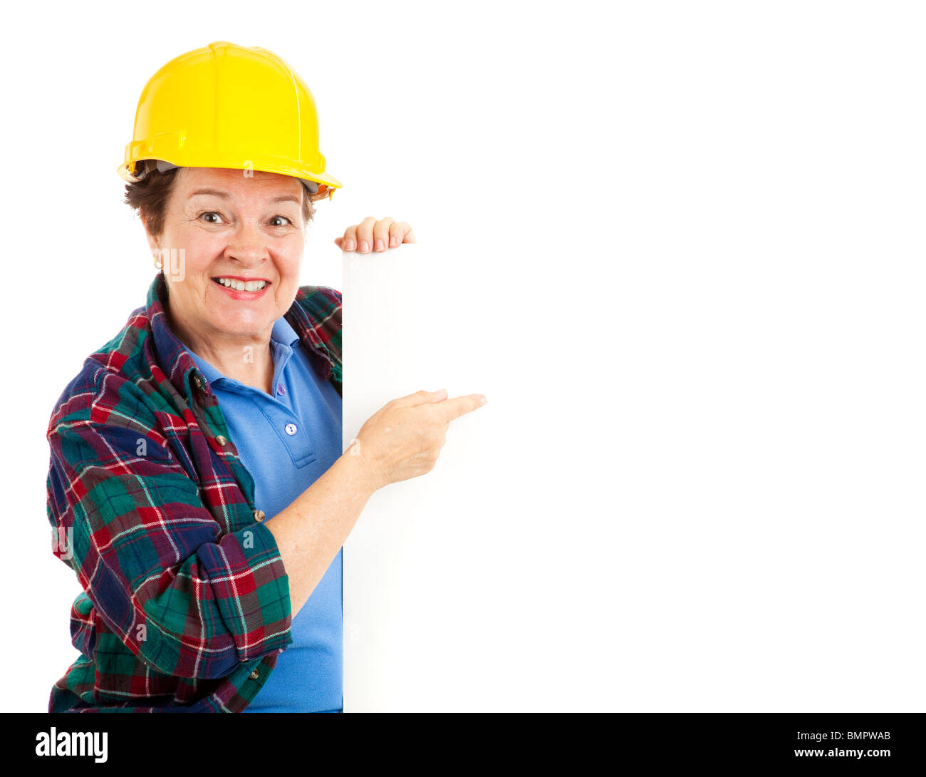 Trabajador de construcción femenina apuntando a un cartel en blanco. Aislado en blanco. Foto de stock