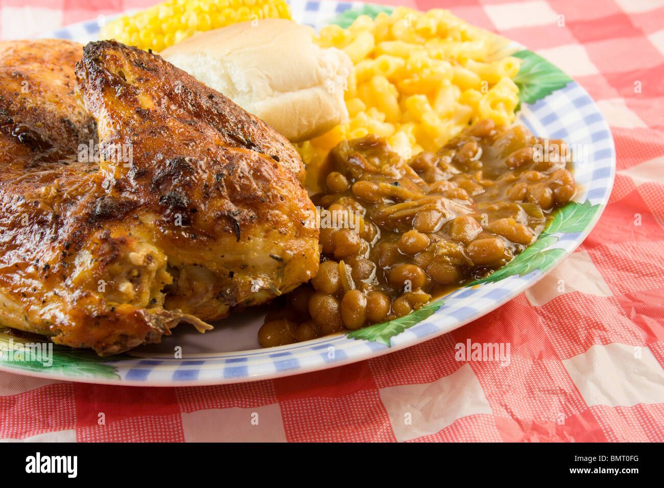 Pollo a la Barbacoa con frijoles, macarrones, estilo picnic sobre un mantel rojo a cuadros Foto de stock
