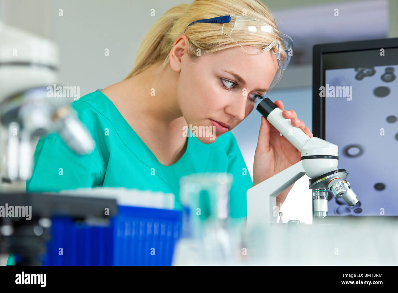 Una hermosa hembra investigador médico o científico o mujer médico con su microscopio en un laboratorio Foto de stock