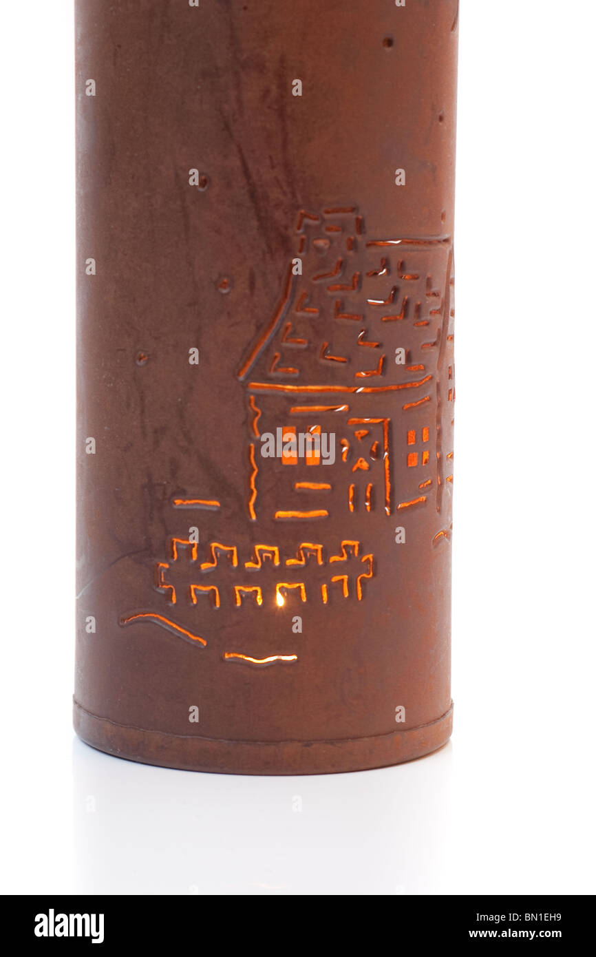 Una botella marrón con un patrón de una casa fuera grabada, exponiendo las velas brillando en su interior, aislado en blanco. Foto de stock