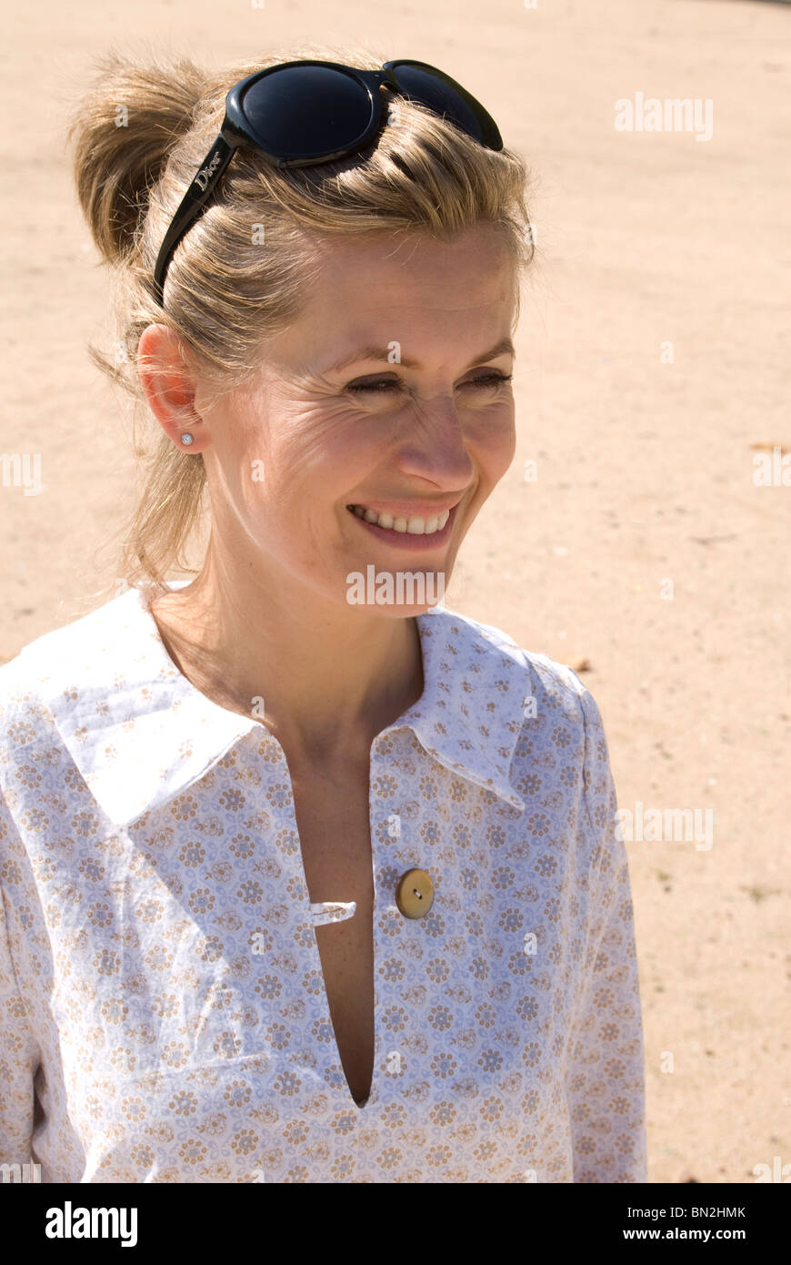 Mujer sonriente apartar la mirada con gafas de sol sobre su cabeza  Fotografía de stock - Alamy