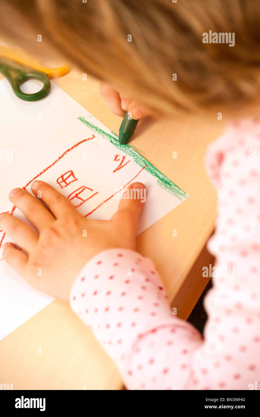 Niña dibujando una imagen con un lápiz de cera, close-up Foto de stock