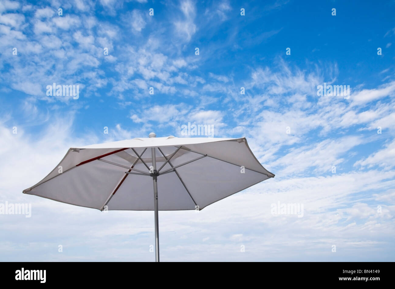 Arriba vista de un patio blanco paraguas abierto contra un bonito cielo en un clima tropical. Foto de stock