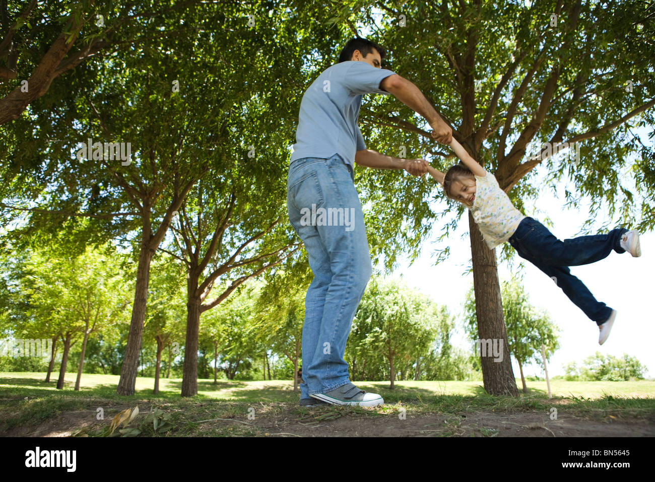 Padre balancea su hija por sus brazos Foto de stock