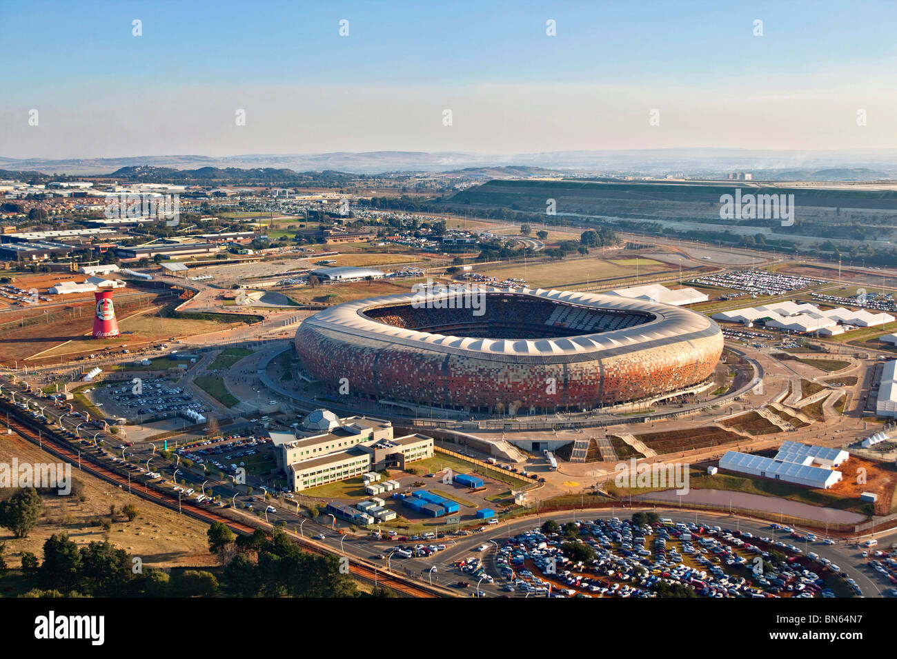 Vista aérea de la FIFA 2010 estadio Soccer City con forma de calabaza con la silueta de la ciudad de Johannesburgo en la distancia Foto de stock