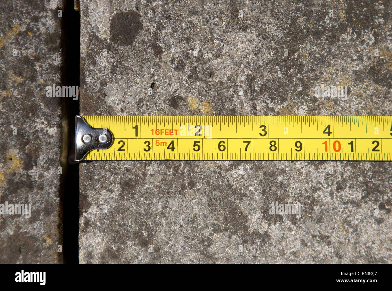 Una cinta métrica mostrando pulgadas y centímetros se muestra la medición  de una losa de hormigón Fotografía de stock - Alamy