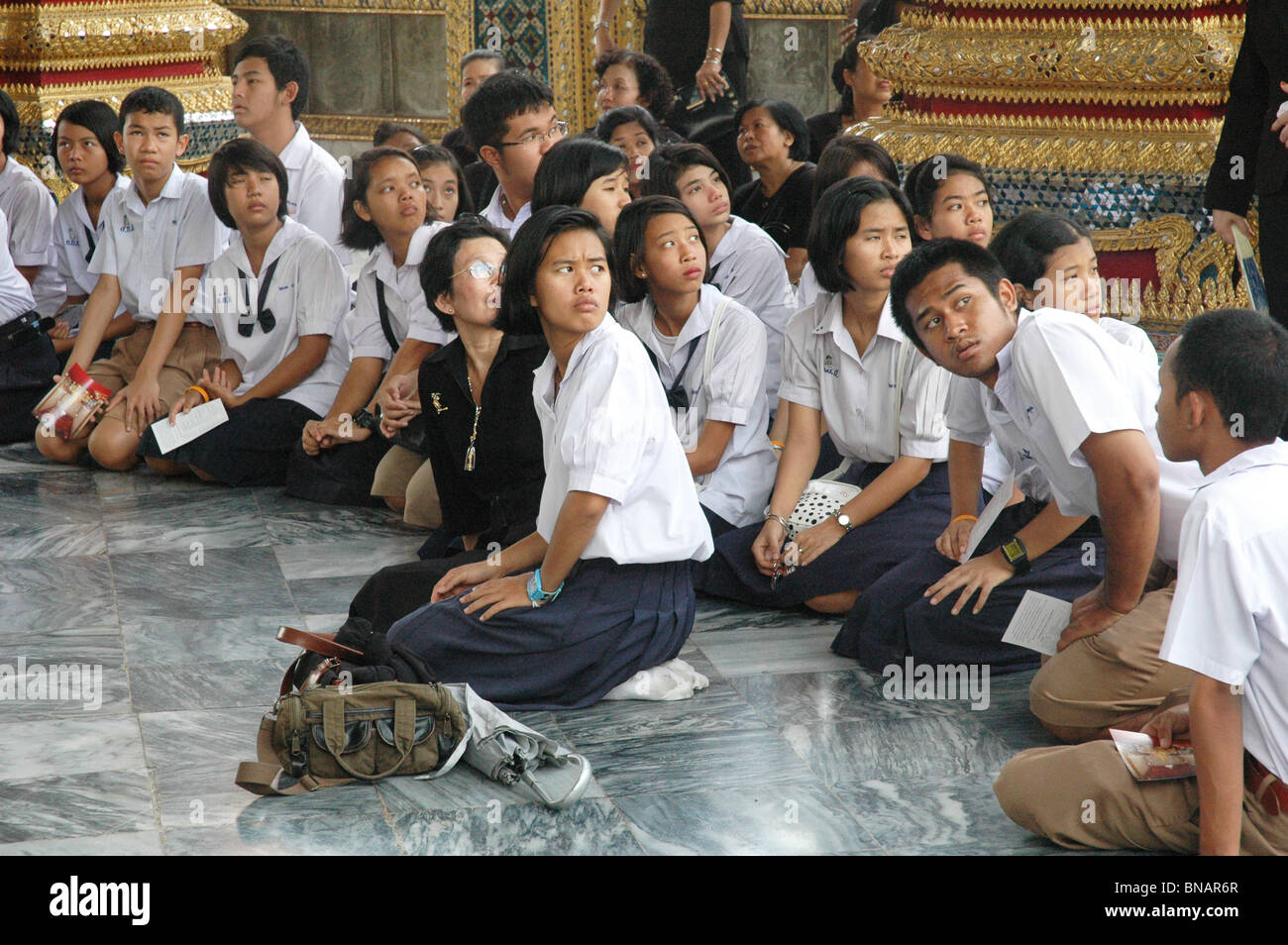 Los estudiantes escuchan atentamente al guía durante la excursión del Gran Palacio de Bangkok Thailand Foto de stock