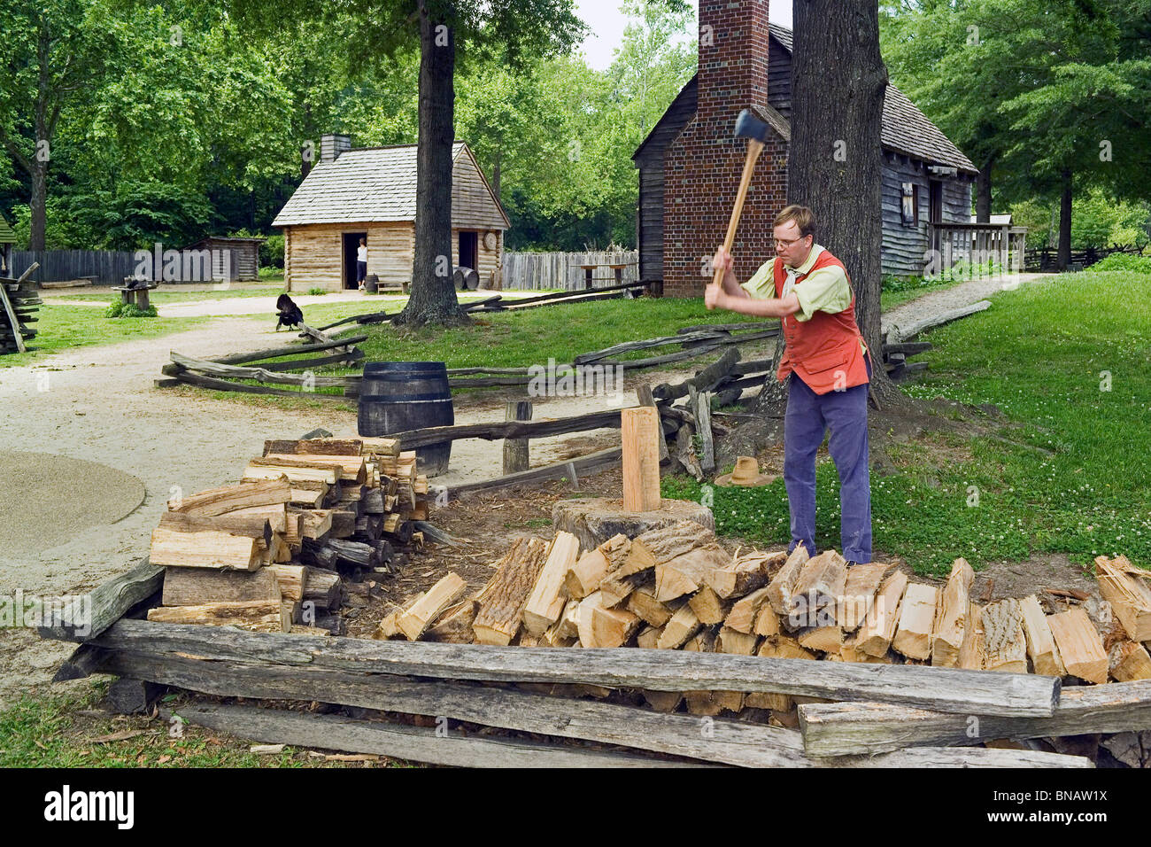 Un intérprete chuletas de madera y trae vida a un re-creado 1780s la granja en el Salón de Historia El Museo de la Revolución Americana en Yorktown, Virginia, EE.UU. Foto de stock