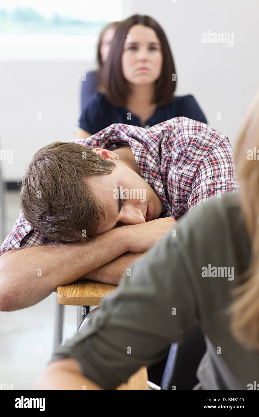 Estudiante de la escuela secundaria masculina dormido en clase Foto de stock