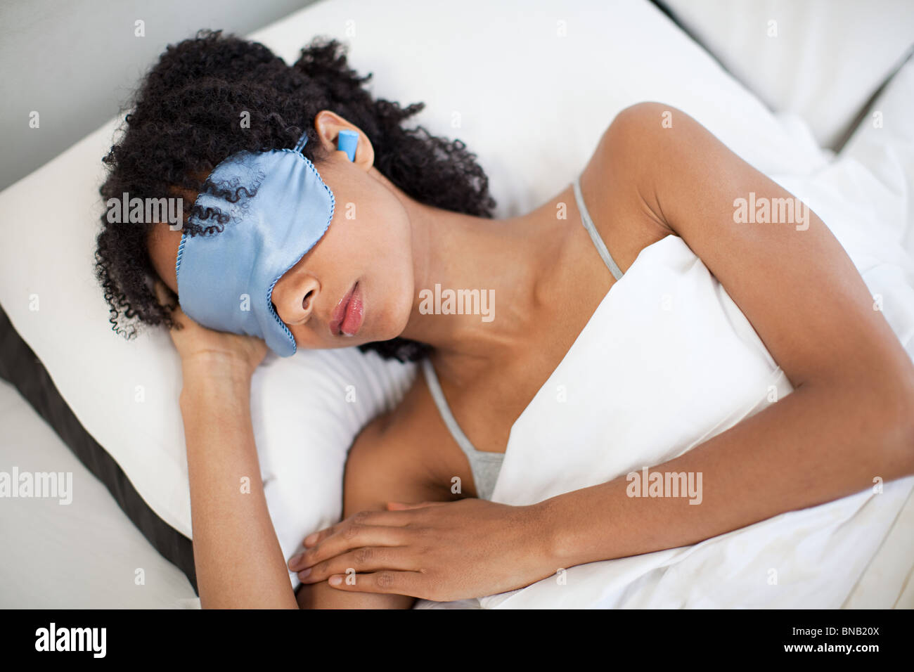 Mujer durmiendo en el ojo máscara y tapones para los oídos. Foto de stock