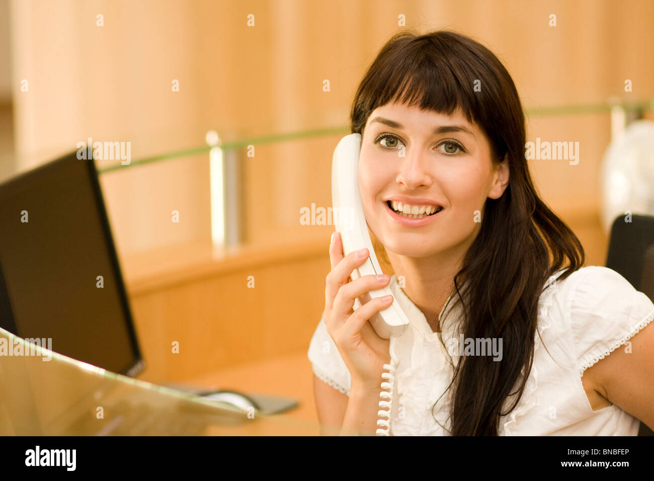 Atractiva mujer joven recepcionista con teléfono Foto de stock