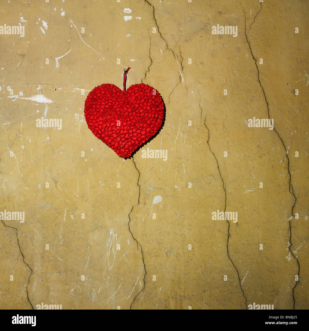 Corazón de papel fijo en una pared agrietada. Foto de stock