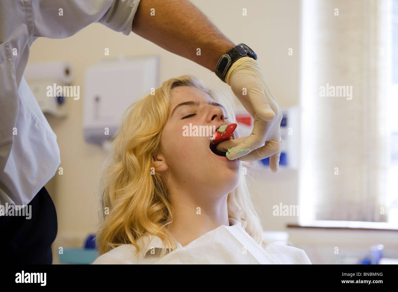 Un servicio nacional de salud ortodoncista teniendo un elenco de una adolescente los dientes, REINO UNIDO Foto de stock
