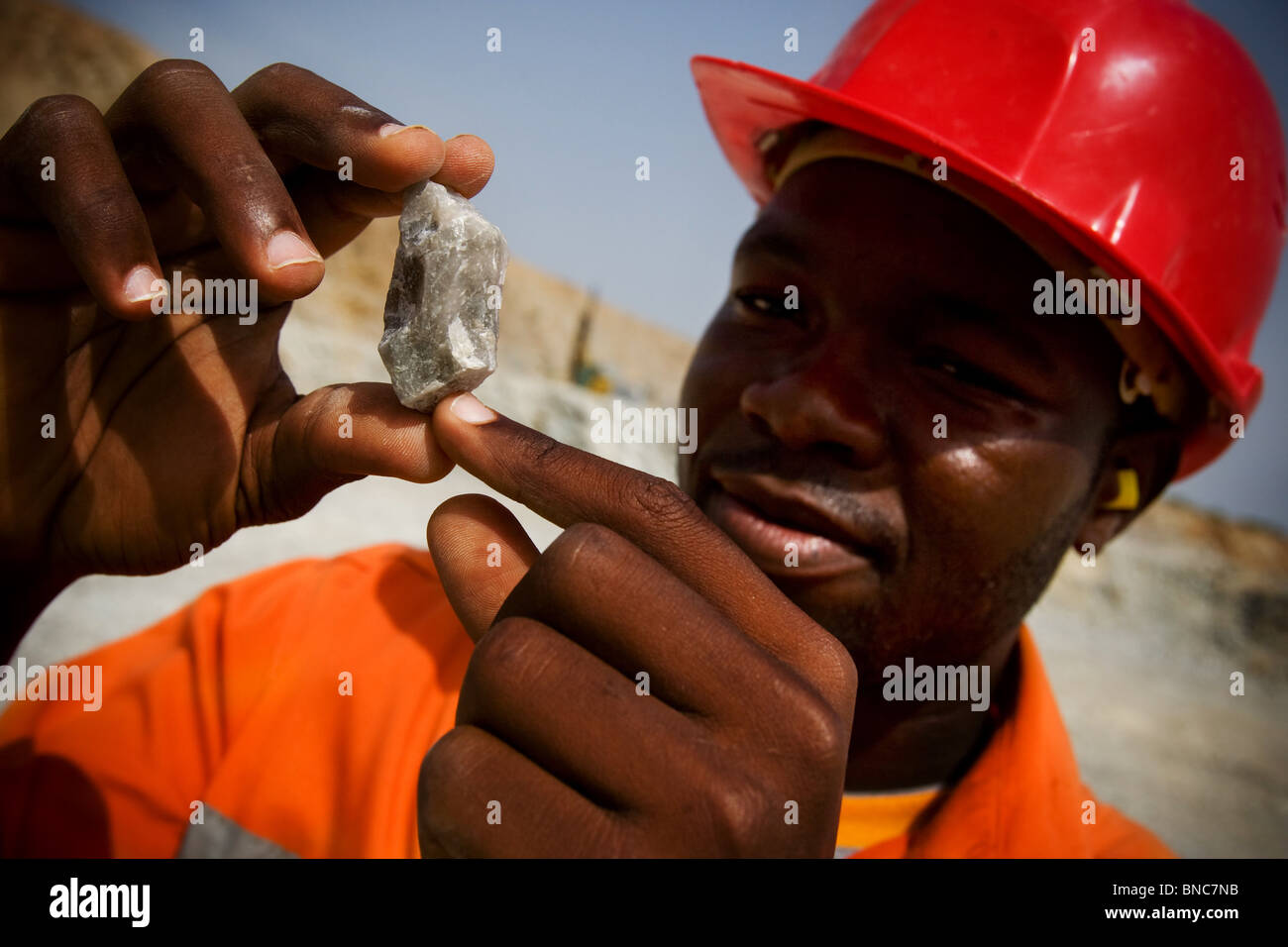 Un trabajador de minas tiene una muestra de mineral dice contiene oro en el pozo principal de la mina de oro de Youga Foto de stock
