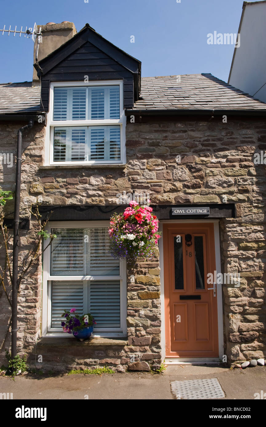 Pintoresca hilera de casas adosadas con cestas colgantes fuera de heno-on-Wye Gales Powys UK Foto de stock