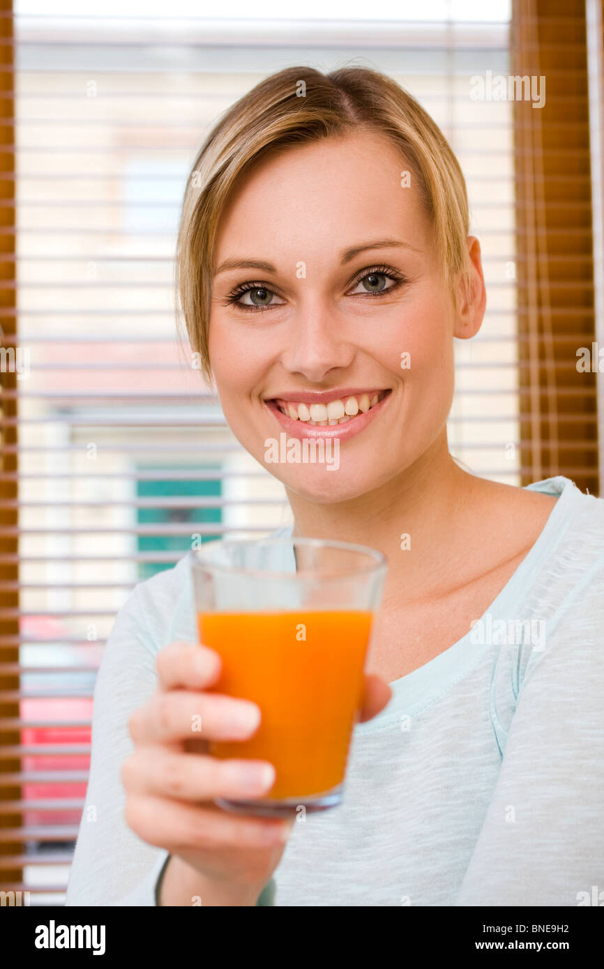 Hermosa joven sosteniendo un vaso de zumo de naranja se centran en su cara Foto de stock