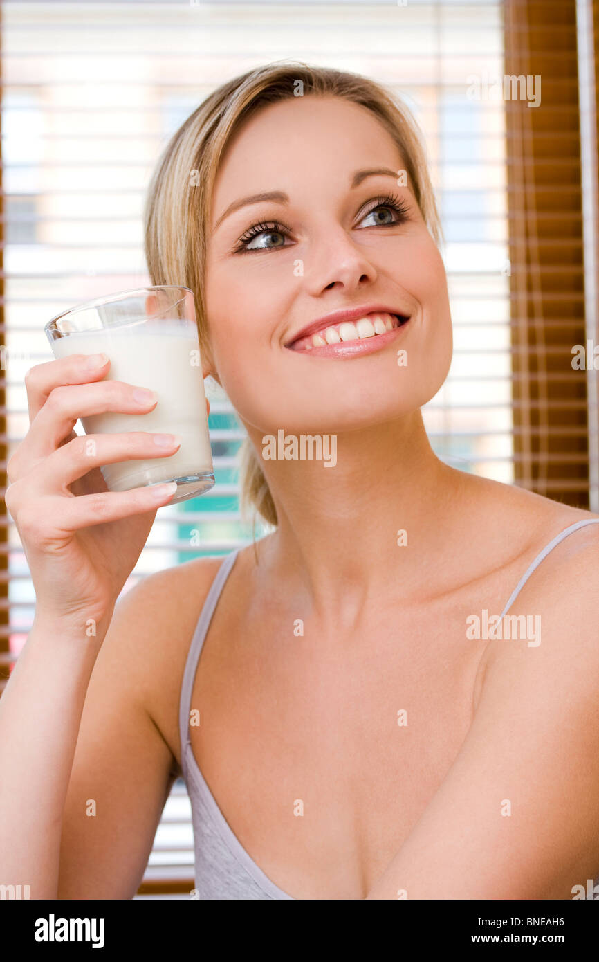 Modelo de estilo de vida la celebración de una leche al lado de su cara Foto de stock