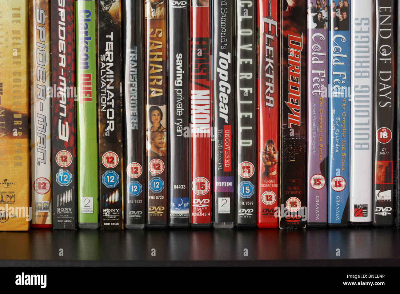 Fila de casos de vídeo DVD en un estante mostrando una gama de BBFC y irish film censores clasificación de oficina avisos desde el reino unido Foto de stock