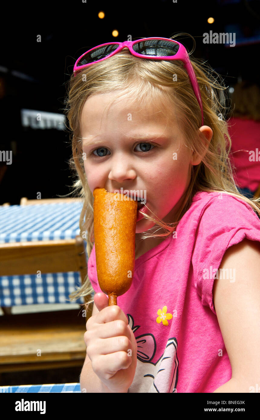 Niña comiendo un corndog en Texas, EE.UU. Foto de stock