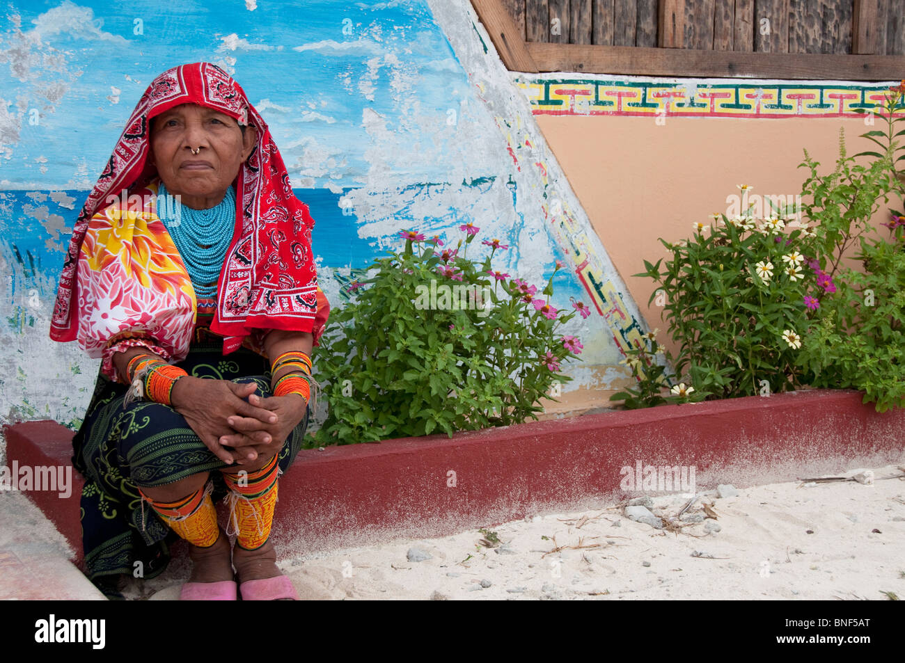 Mujer en traje tradicional sentado delante de una pared, las Islas de San Blas, Kuna Yala, Panamá Foto de stock