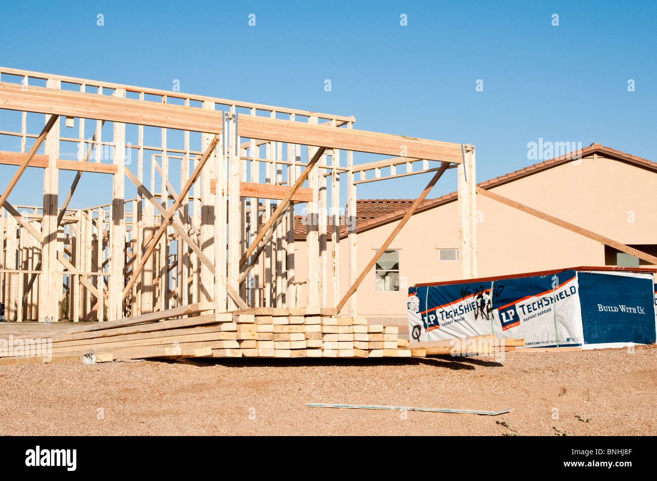 Los materiales de construcción están apilados en el sitio de construcción de un nuevo marco de madera casa beign construido en Arizona. Foto de stock