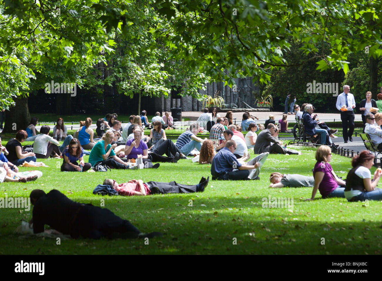 Las personas relajante sobre el césped durante el almuerzo en el parque St Stephen's Green, Dublín, Irlanda Foto de stock