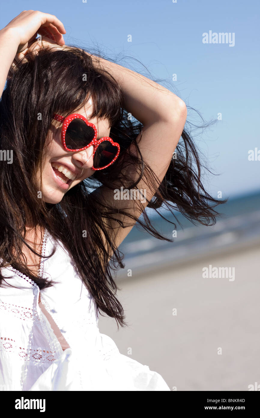Retrato de mujer joven feliz con elegantes gafas de sol jugando con su cabello Foto de stock