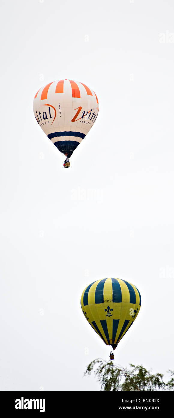 Dos globos de aire caliente que luchan para ganar altura sobre Alsager Cheshire, Inglaterra, Reino Unido Foto de stock