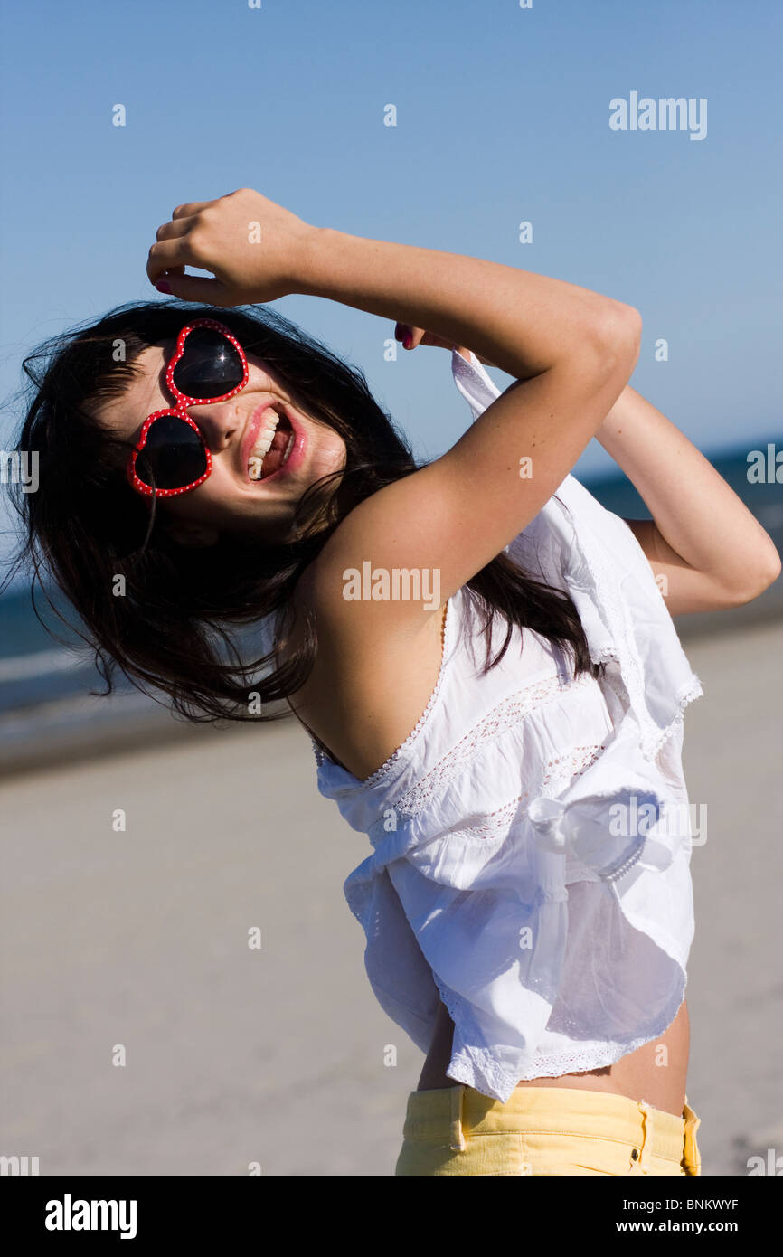 Retrato de mujer joven feliz con elegantes gafas de sol jugando con su cabello Foto de stock