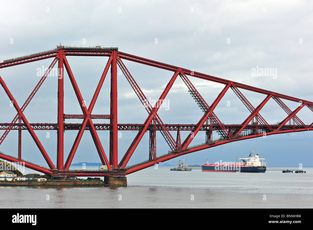 Petrolero navegando bajo el Forth Railway Bridge / puente ferroviario de Forth, un puente sobre el Firth of Forth, cerca de Edimburgo, Escocia Foto de stock