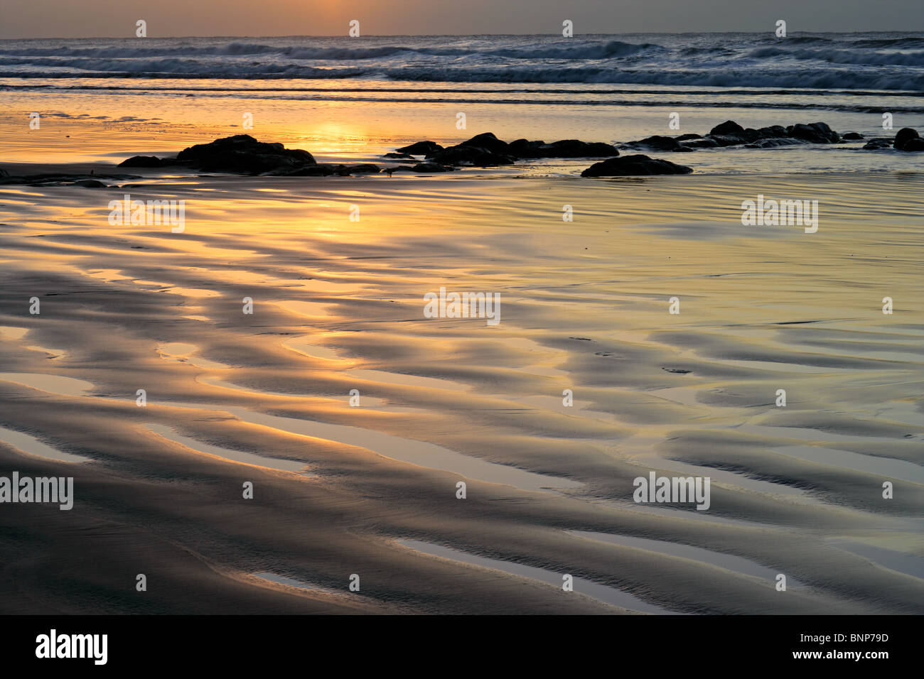 Seascape al amanecer con reflejos dorados y rocas costeras Foto de stock