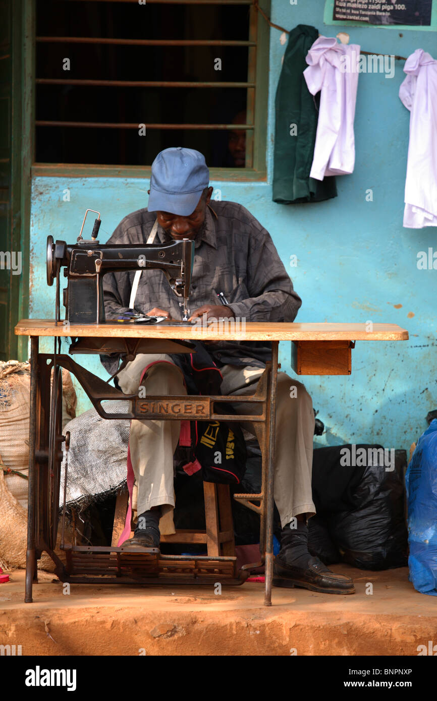 Hombre sastre coser prendas con cantante tradicional, Tanzania Foto de stock