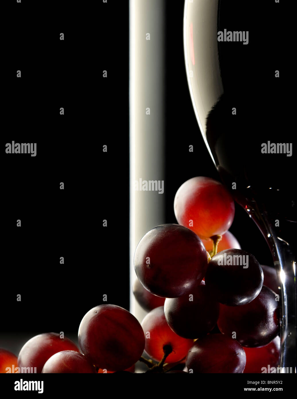 Close-up de las uvas rojas y un vaso o botella de vino tinto Foto de stock
