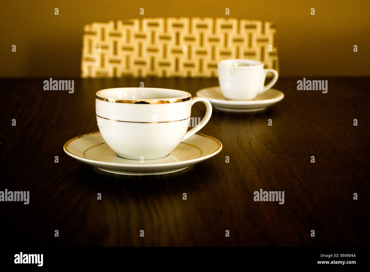 2 tazas de café espresso 1 sobre una mesa con silla en el fondo café dos tazas de café Foto de stock