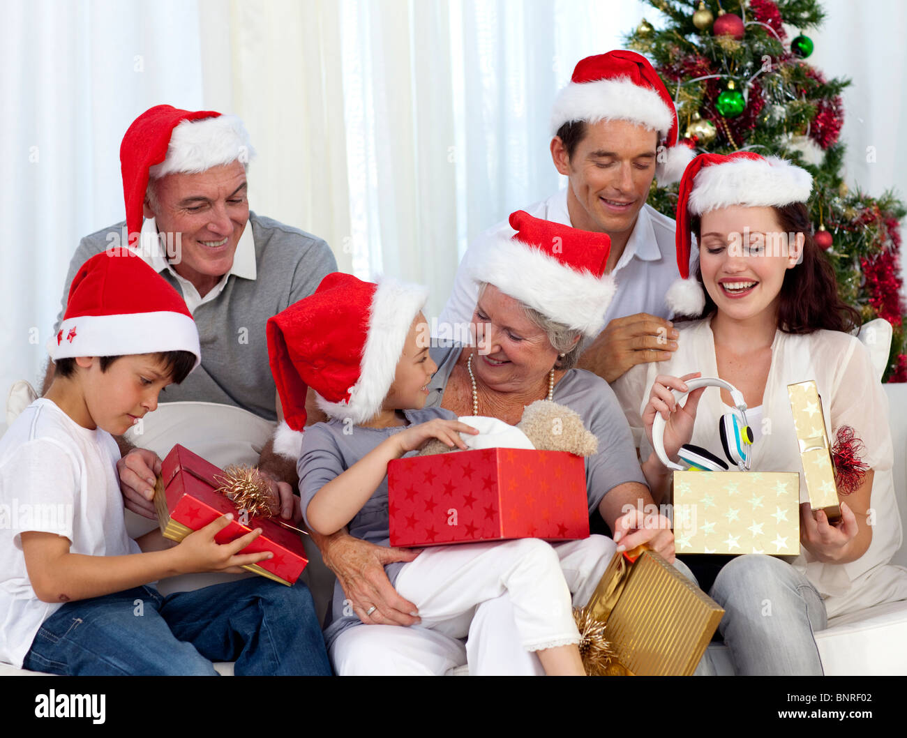 Familia abriendo regalos de Navidad en casa Fotografía de stock - Alamy