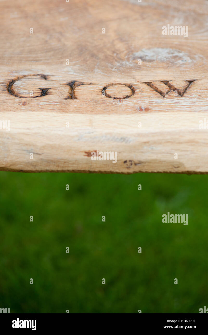 Banco de jardín de madera tallada con la palabra 'Crecer' en RHS Harlow Carr Foto de stock