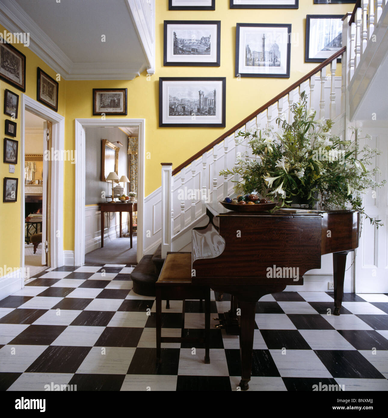 Gran arreglo floral en grand piano en amarillo país hall con escalera de  color blanco y negro+blanco cuadriculado piso de vinilo Fotografía de stock  - Alamy