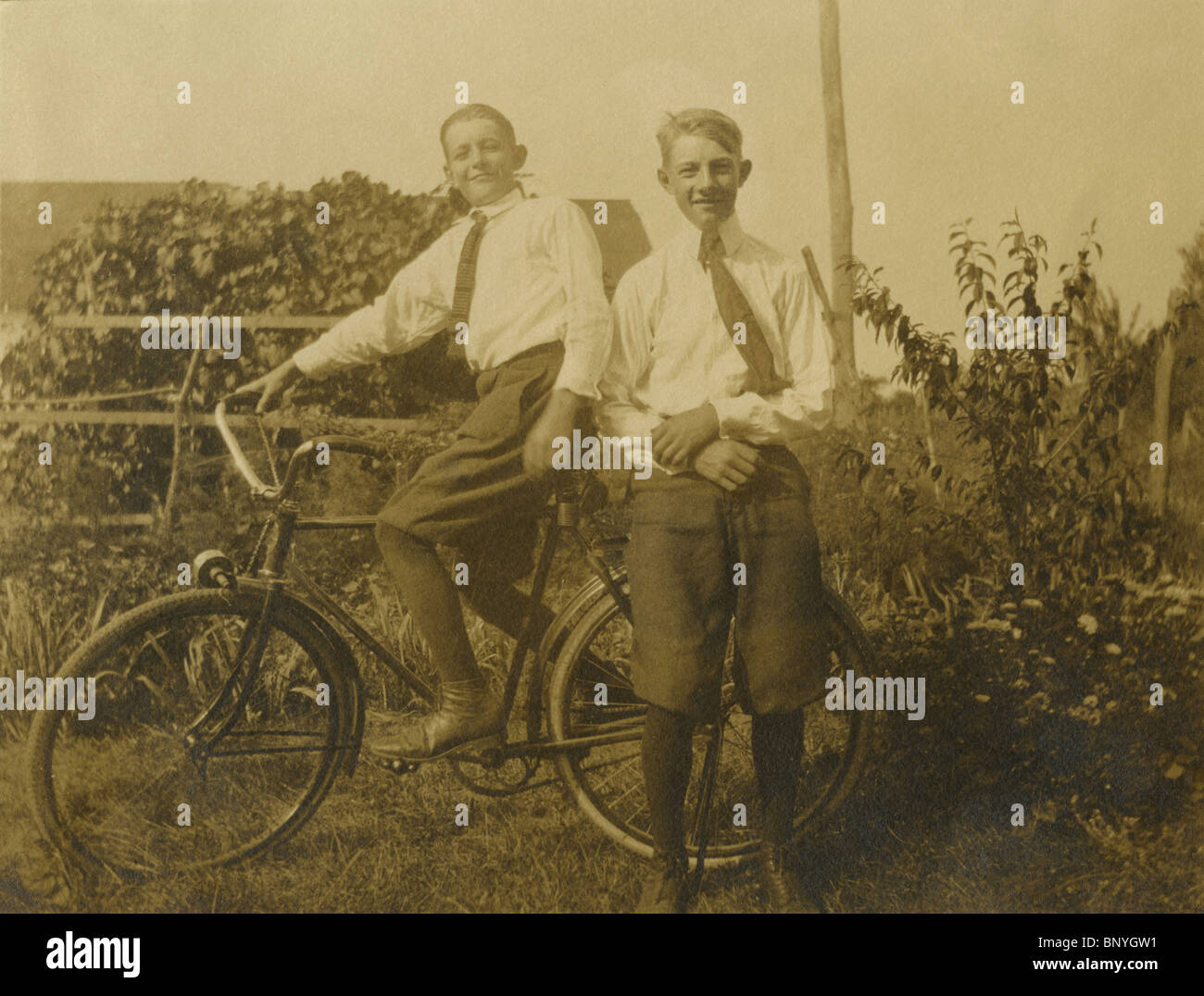 C1910 fotografía de dos niños montando una antigua bicicleta. Foto de stock