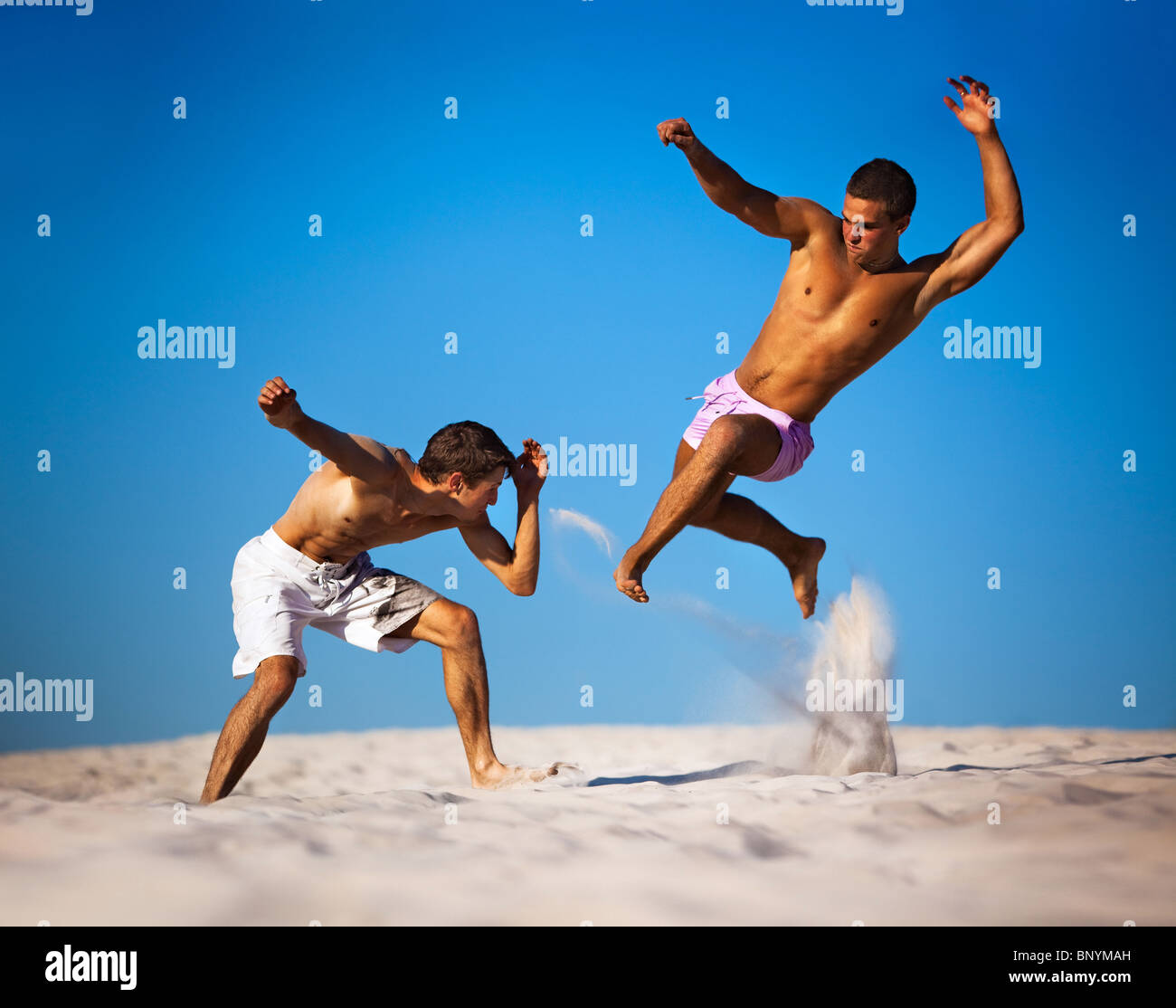 Dos hombres jóvenes deporte luchando en la playa. Foto de stock