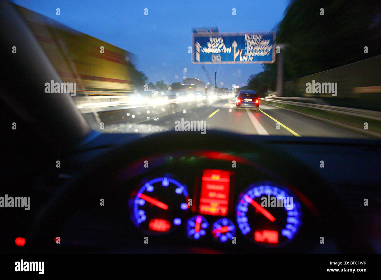 Conducir al atardecer en la autopista. Las luces del salpicadero, iluminado, el velocímetro, el tiempo lluvioso condición. Foto de stock