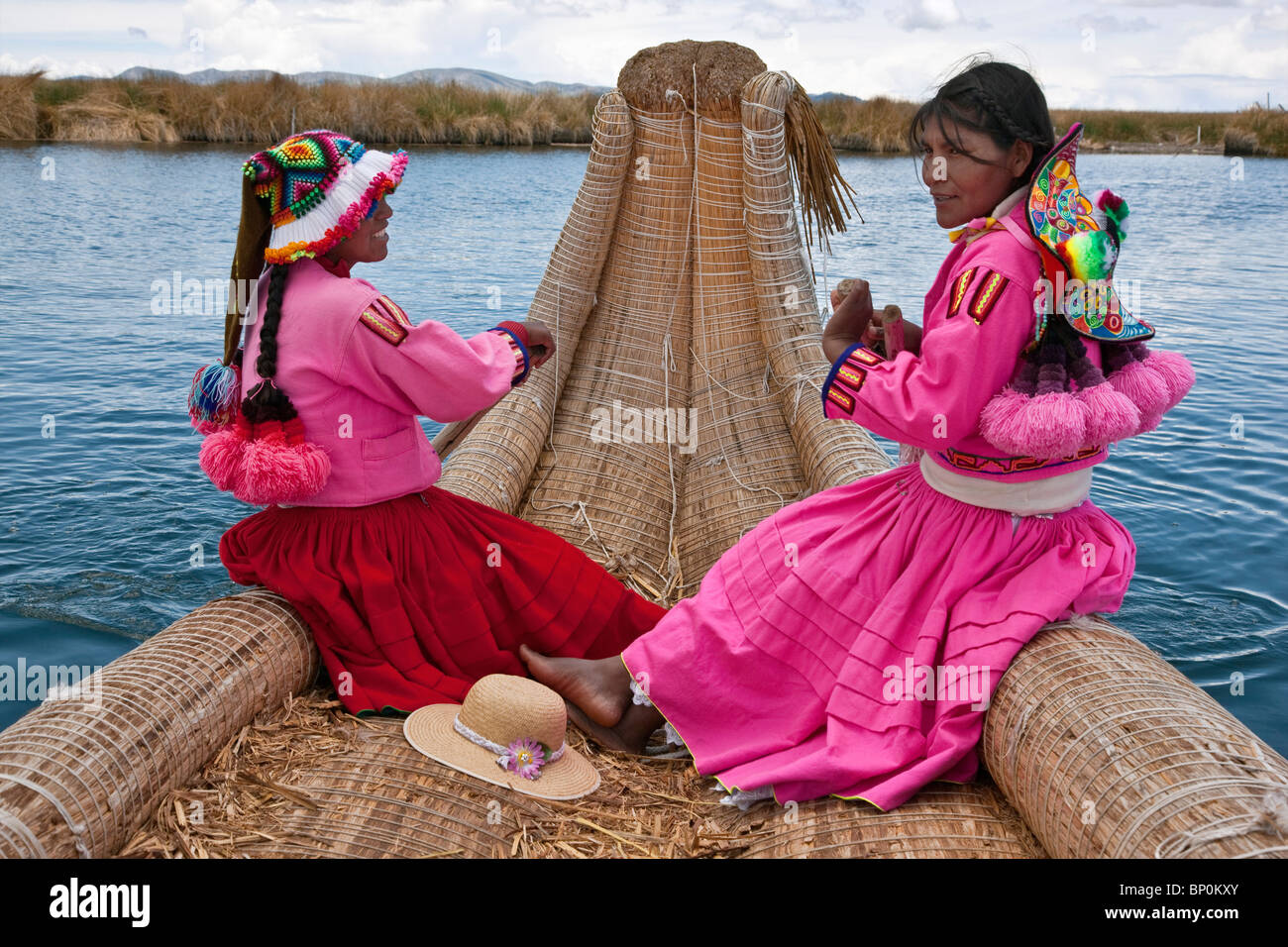 Perú, dos niñas de Uros fila a Reed barco a una de las singulares islas flotantes del lago Titicaca. Foto de stock