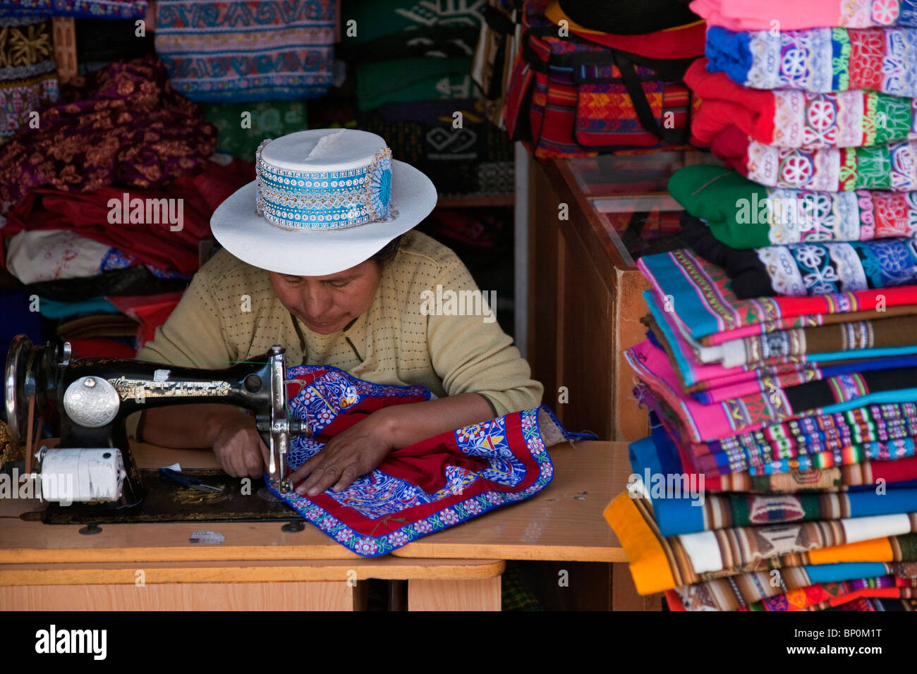 Perú, una mujer usa su máquina de coser a bordar en tela en una tienda en Chivay, capital de la provincia de Caylloma. Foto de stock