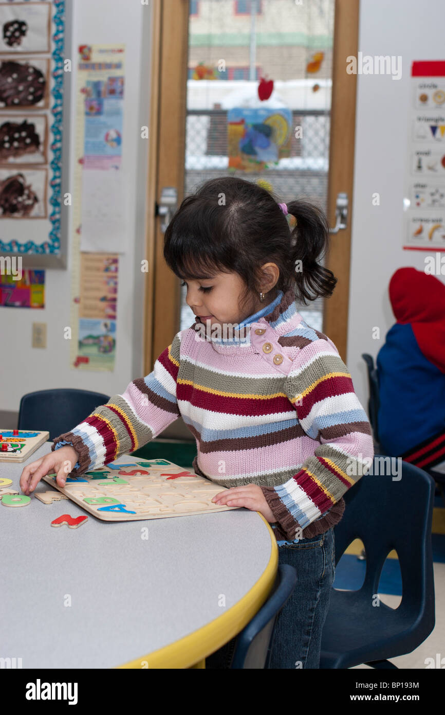 Aula preescolar Niña preescolar de 4 años componiendo un puzzle en la escuela Fotografía de stock - Alamy